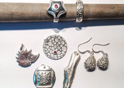Art Clay ezüstgyurma workshop - ezüstékszer kollekció: két ezüstgyűrű, egy medál kőbefogással, egy sünt formázó medál, egy napot formázó medál, egy levelet formázó medál és egy pár fecskendős technikával készült fülbevaló.